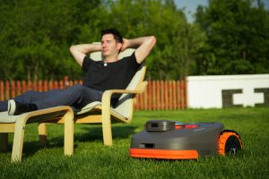 Homeowner relaxing while a segway navimow is mowing the lawn